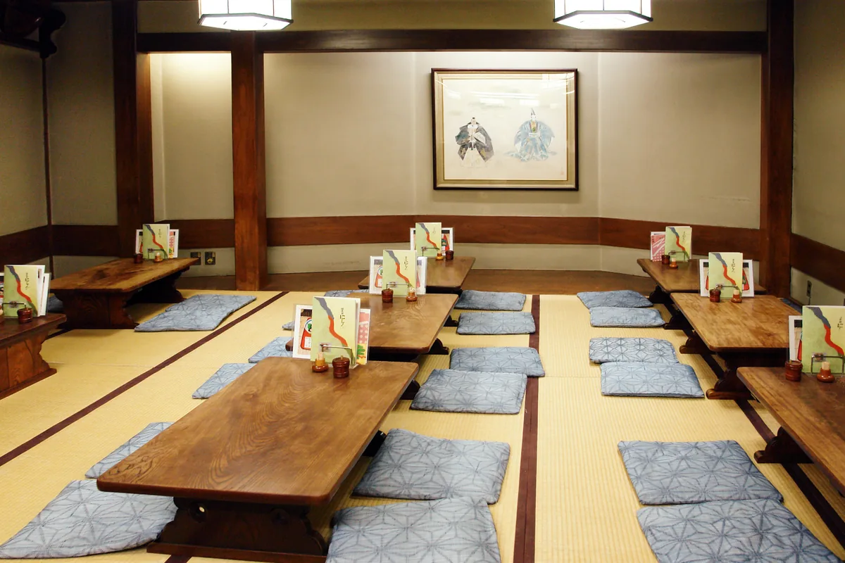 A tatami dining room with low tables and floor cushions, representative of traditional Japanese boat seating